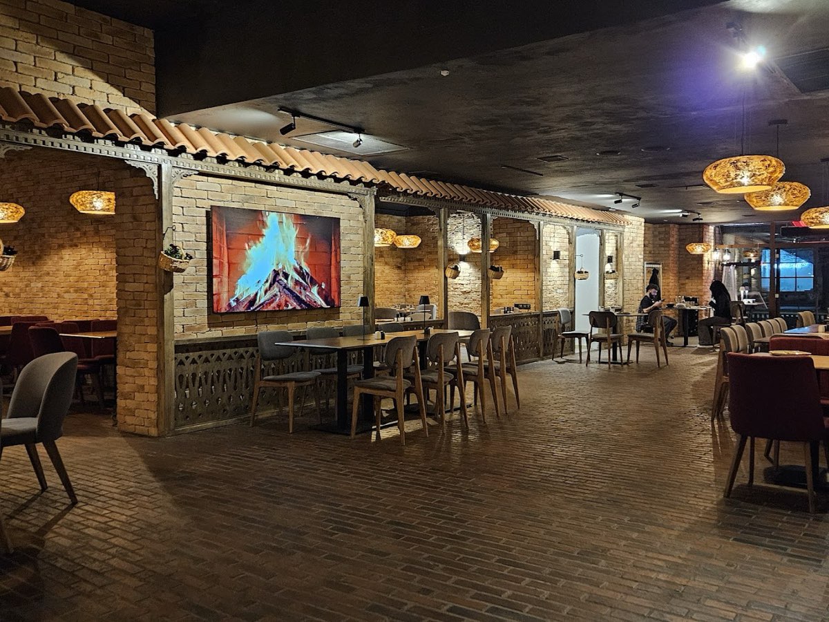 Ceglane wnętrze restauracji z ciepłymi lampami i obrazem ognia