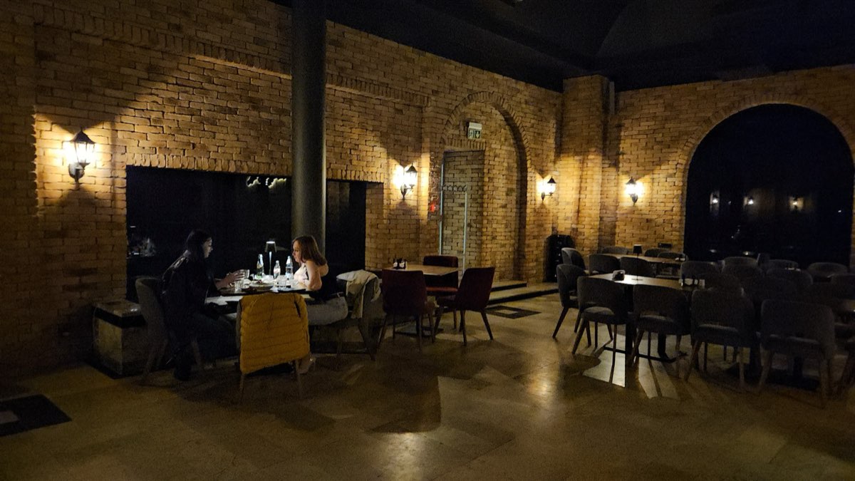 Ceglane, sklepione wnętrze restauracji oświetlone ciepłem kinkietów