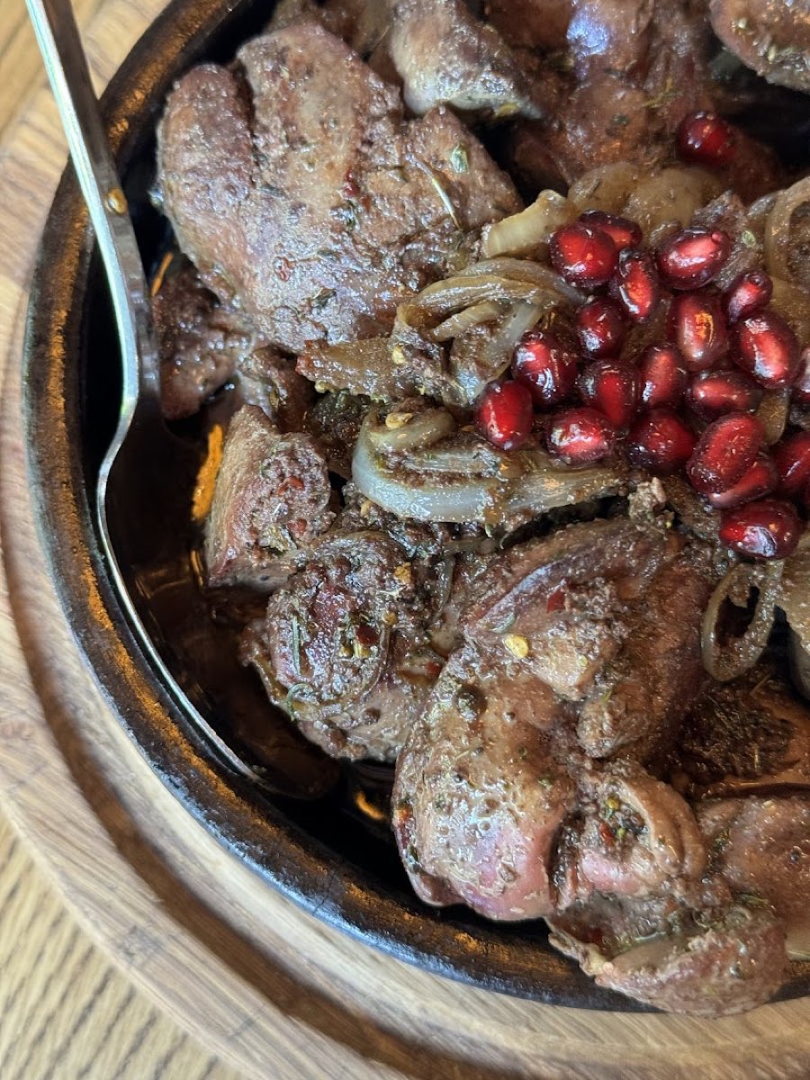 Grillowane mięso z cebulą i pestkami granatu w żeliwnym naczyniu